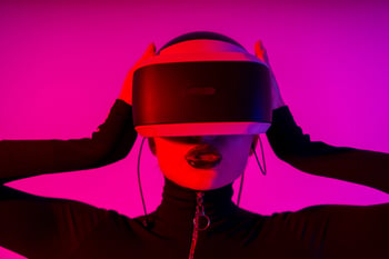 Una chica utiliza unos visores VR en un entorno que parece futurista, con un fondo en luces neón. 