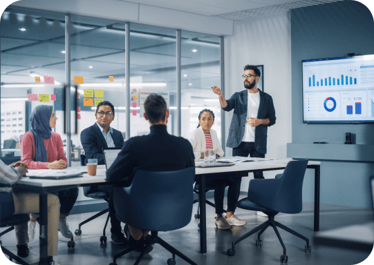 Un equipo de colaboradores analiza unas gráficas en una pantalla led gigante, mientras uno de ellos expone. Todos se encuentran en el interior de una sala de juntas. Un equipo de colaboradores analiza unas gráficas en una pantalla led gigante, mientras uno de ellos expone. Todos se encuentran en el interior de una sala de juntas.