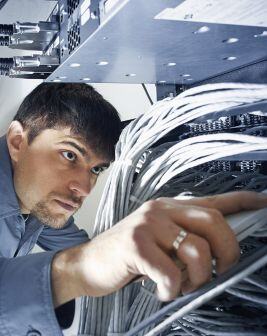 Un instalador revisa el cableado de un rack en el interior de un centro de datos. 