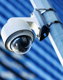 Una cámara de vigilancia tipo domo se encuentra instalada en el exterior de un entorno corporativo. 