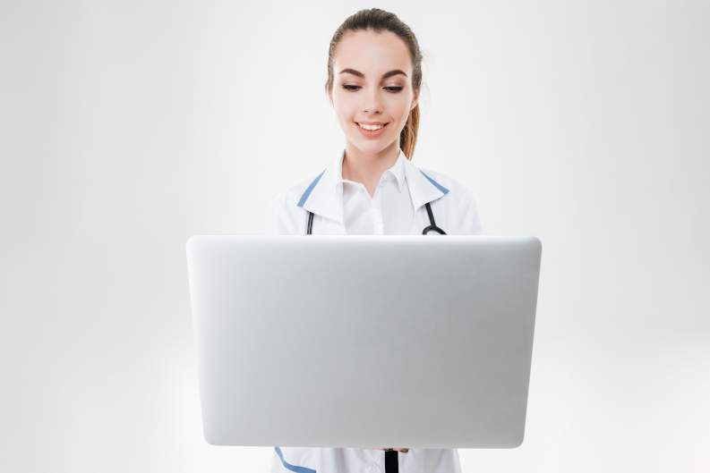 Una doctora sonriente sostiene una laptop para conectarse con un paciente. 