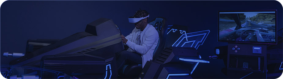 Foto de un adolescente jugando en un simulador de carreras. Está montando en un coche de juego y porta visores VR.