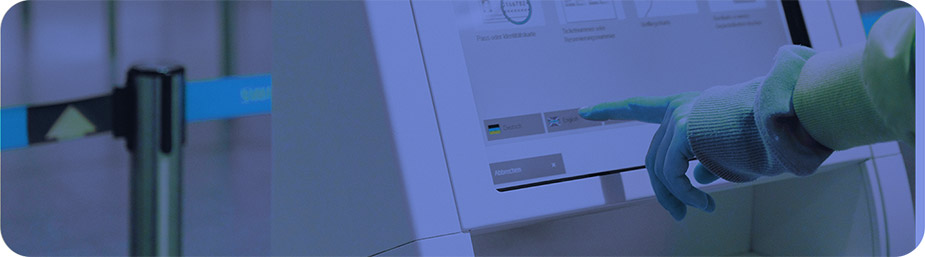 Una mano presiona la pantalla touch de un kiosko digital. 