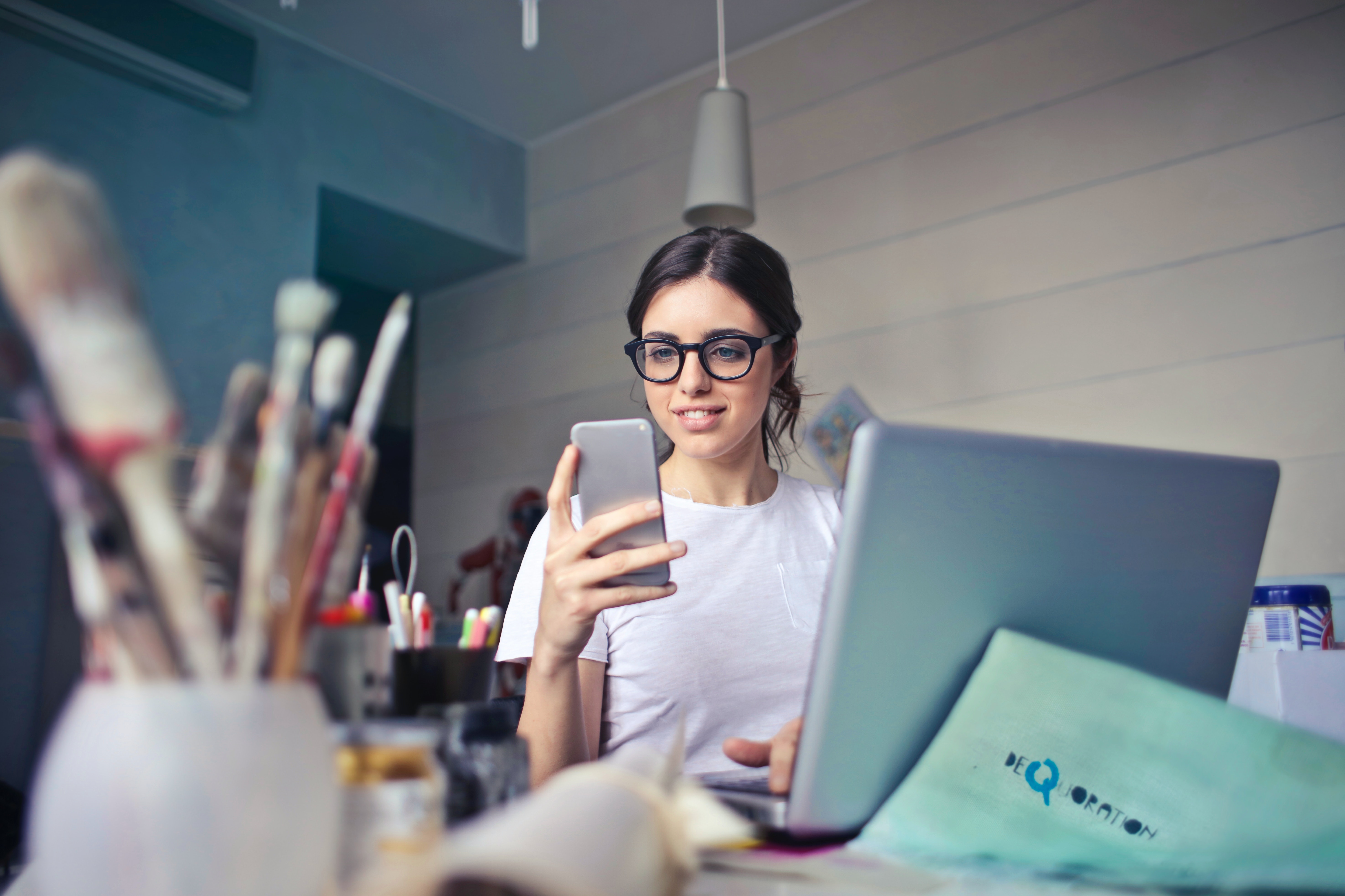 Una joven se encuentra en su lugar de trabajo y revisa su smartphone. Su dispositivo también puede usarse como teléfono IP. 