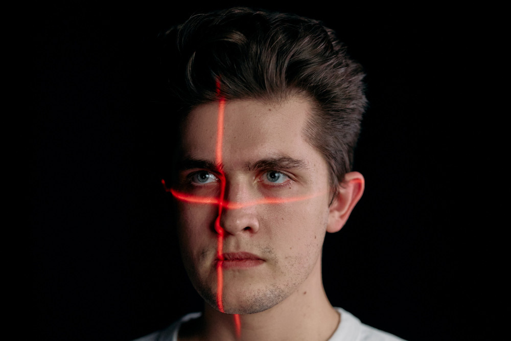 Una figura color rojo en forma de X se proyecta en el rostro de hombre que podría ser considerado un intruso. 