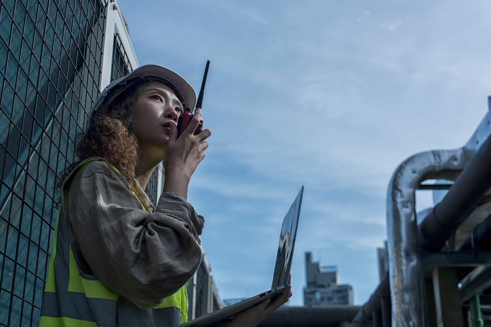 Trabajadora en una central de carga utiliza un radiocomunicador para hablar con su equipo de logística. 